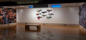 Gallery view of large printed collages and aquatic larva sculptures
