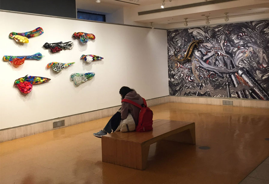 Gallery visitor sitting on a bench in front of sculptures